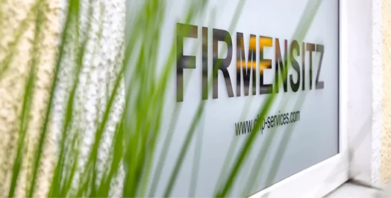 Firmenschild „FIRMENSITZ“ hinter Pflanzen als Symbol für eine professionelle Domiziladresse.
