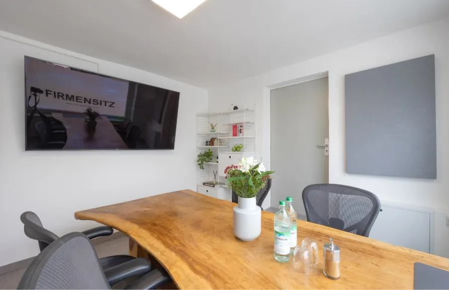 Heller Besprechungsraum mit Holztisch und Stühlen als Beispiel für ein physisches Büro.